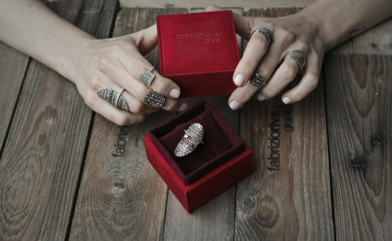 A Person Wearing Silver Rings while Holding a Red Box